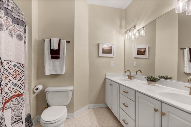 full bath with double vanity, a sink, toilet, and baseboards