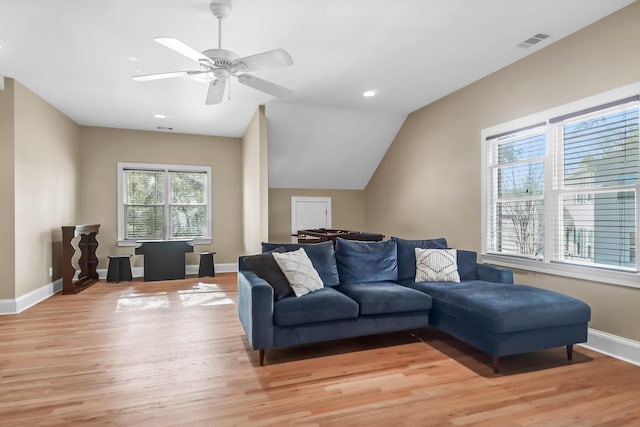 living room with light wood-style floors, lofted ceiling, visible vents, and baseboards