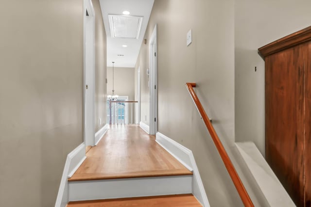 stairway featuring wood finished floors, attic access, and baseboards