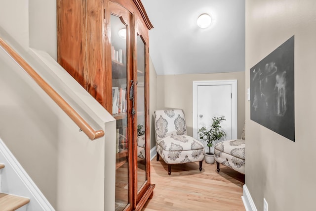 corridor with vaulted ceiling, stairway, wood finished floors, and baseboards