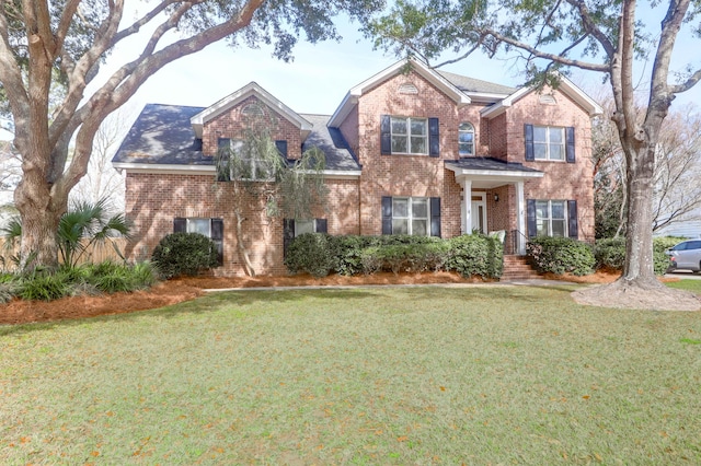 traditional-style house featuring a front yard and brick siding