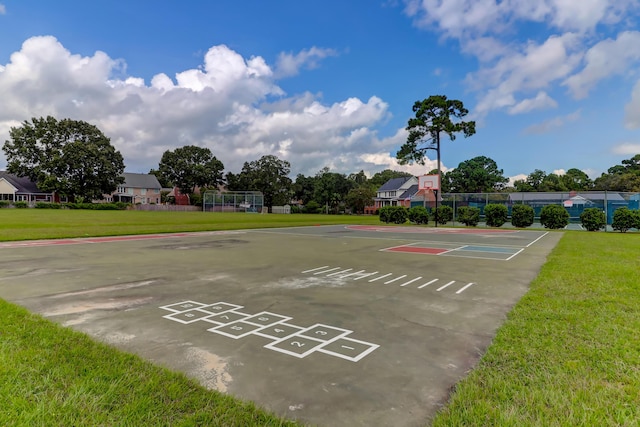 view of community featuring uncovered parking, fence, and a lawn