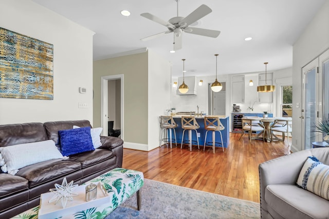 living area with recessed lighting, beverage cooler, wood finished floors, a ceiling fan, and baseboards