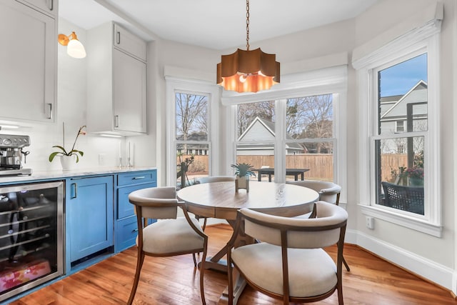 dining room featuring beverage cooler, baseboards, and light wood-style flooring