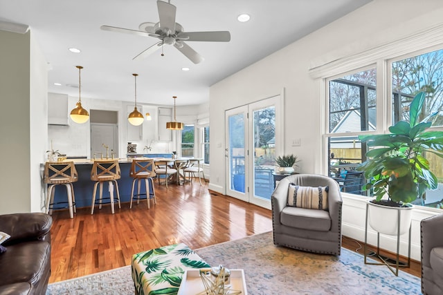 living area featuring a ceiling fan, recessed lighting, baseboards, and wood finished floors