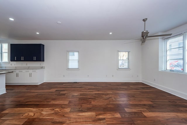 unfurnished living room with ceiling fan, plenty of natural light, and dark wood-type flooring