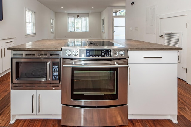 kitchen with white cabinets, appliances with stainless steel finishes, dark wood-type flooring, and a healthy amount of sunlight