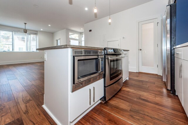 kitchen featuring white cabinets, dark hardwood / wood-style floors, hanging light fixtures, and appliances with stainless steel finishes