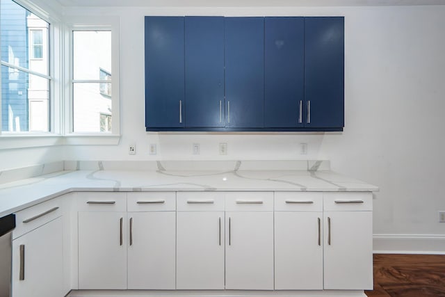 kitchen with white cabinets, stainless steel dishwasher, light stone counters, and blue cabinetry