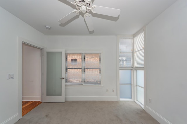 empty room with light colored carpet, plenty of natural light, and ceiling fan