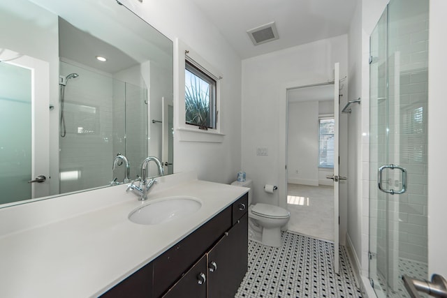 bathroom featuring vanity, toilet, plenty of natural light, and a shower with shower door