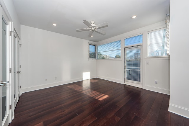 unfurnished room featuring a wealth of natural light, ceiling fan, and dark hardwood / wood-style floors