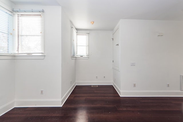 spare room featuring plenty of natural light and dark wood-type flooring