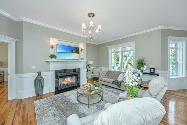 living room with light hardwood / wood-style flooring, a chandelier, a fireplace, and crown molding