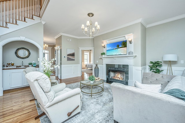 living room featuring ornamental molding, sink, light wood-type flooring, and a tile fireplace