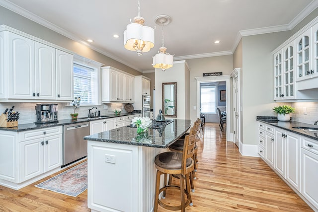 kitchen with light hardwood / wood-style floors, a healthy amount of sunlight, stainless steel dishwasher, and a kitchen island