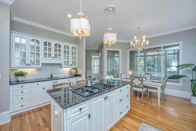 kitchen with white cabinetry, light hardwood / wood-style flooring, ornamental molding, decorative light fixtures, and a center island