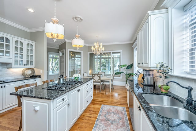 kitchen with sink, stainless steel appliances, pendant lighting, white cabinets, and light hardwood / wood-style flooring