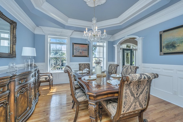 dining space with light hardwood / wood-style floors, a raised ceiling, and ornamental molding