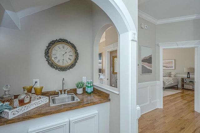 4233 Haulover Dr, Johns Island, SC 29455 - indoor wet bar featuring ornamental molding, light wood-style flooring, wainscoting, and arched walkways