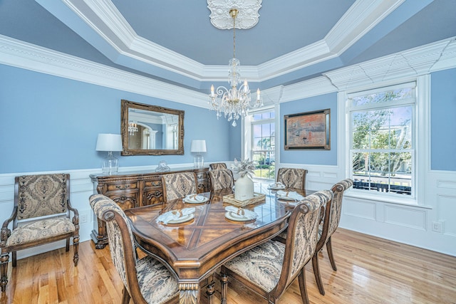 dining room with crown molding, hardwood / wood-style flooring, a tray ceiling, and plenty of natural light