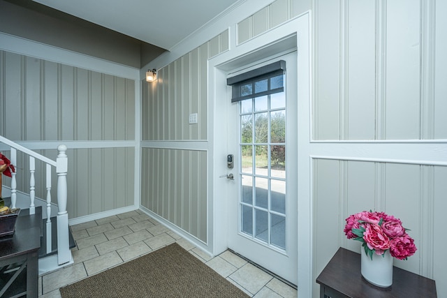 doorway with ornamental molding and light tile patterned flooring