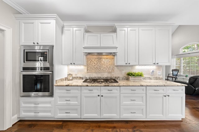 241 Clubside Dr, Lexington, SC 29072 - kitchen featuring appliances with stainless steel finishes, white cabinetry, custom range hood, light stone counters, and tasteful backsplash