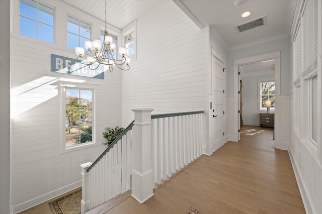 hallway with a chandelier, light hardwood / wood-style flooring, and ornamental molding