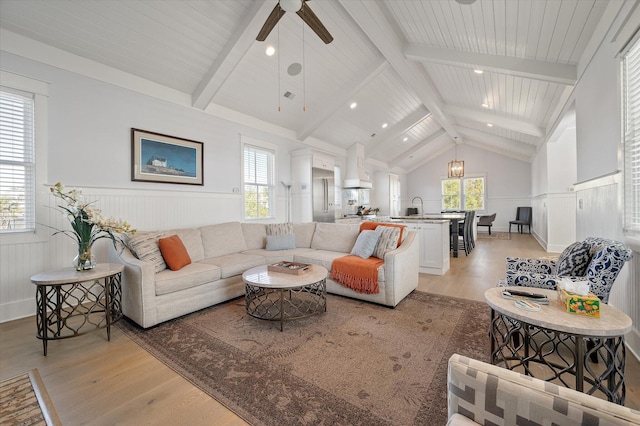 living room with a wealth of natural light, lofted ceiling with beams, light hardwood / wood-style floors, and ceiling fan