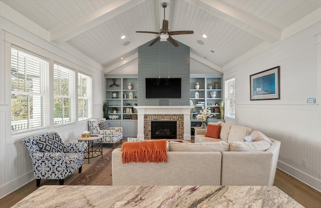 living room with ceiling fan, lofted ceiling with beams, built in features, a fireplace, and dark hardwood / wood-style floors