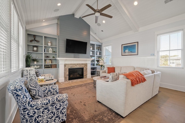 living room featuring ceiling fan, lofted ceiling with beams, hardwood / wood-style flooring, built in features, and a fireplace