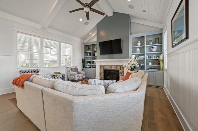 living room with built in shelves, dark hardwood / wood-style flooring, a fireplace, and vaulted ceiling with beams