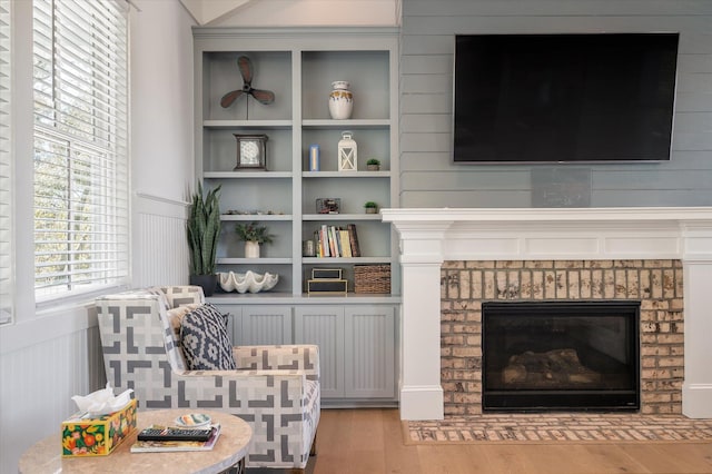 living area with light wood-type flooring and a brick fireplace