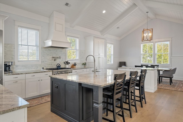 kitchen featuring light stone countertops, light hardwood / wood-style flooring, white cabinets, and hanging light fixtures