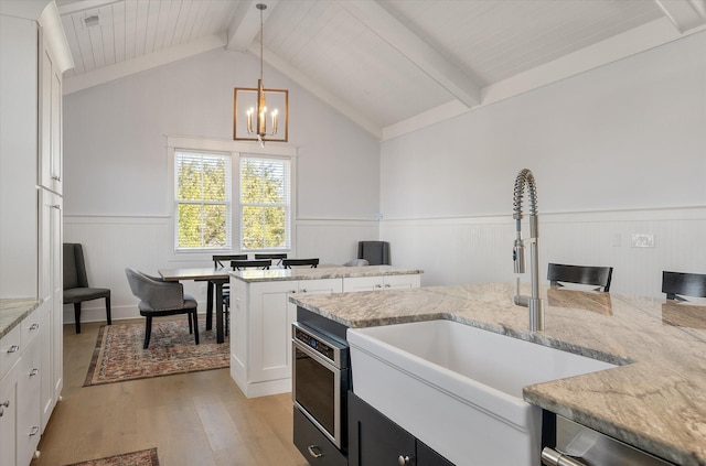 kitchen featuring white cabinets, vaulted ceiling with beams, hanging light fixtures, and sink