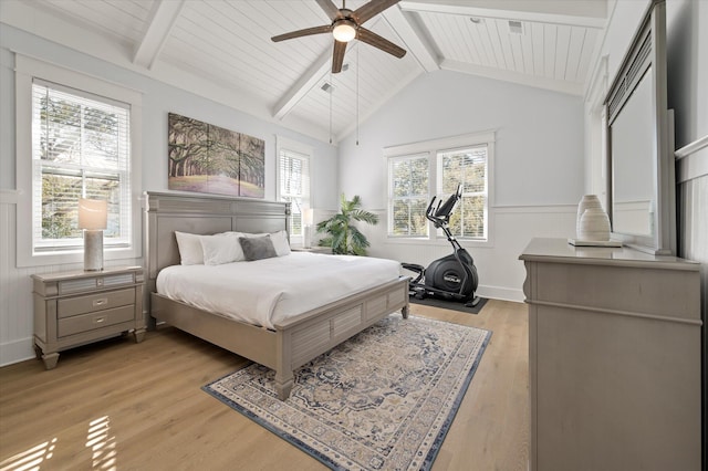 bedroom with multiple windows, ceiling fan, lofted ceiling with beams, and light wood-type flooring