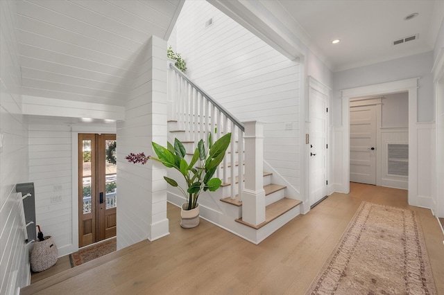 entrance foyer featuring wood walls, french doors, and light hardwood / wood-style floors