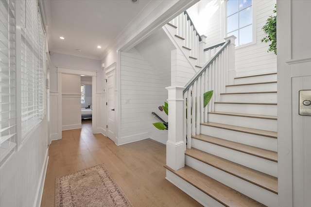 stairway with wood-type flooring and ornamental molding