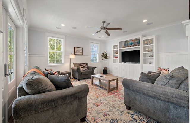 living room featuring built in features, ceiling fan, and crown molding