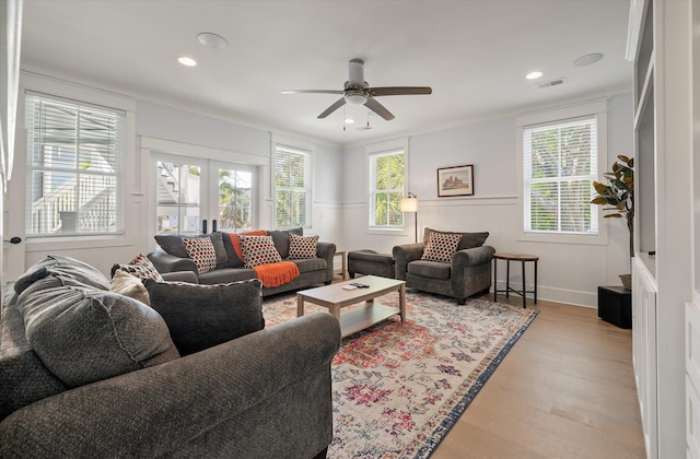 living room with light wood-type flooring, crown molding, a wealth of natural light, and french doors