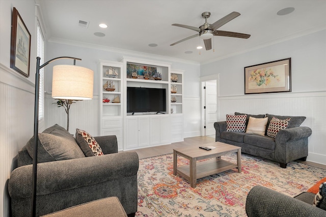 living room with built in shelves, crown molding, and ceiling fan