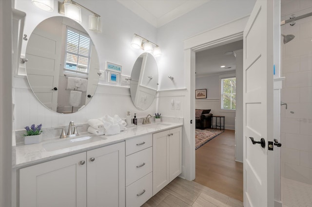 bathroom with tiled shower, hardwood / wood-style flooring, vanity, and ornamental molding