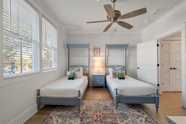 bedroom with dark hardwood / wood-style flooring, ceiling fan, and crown molding