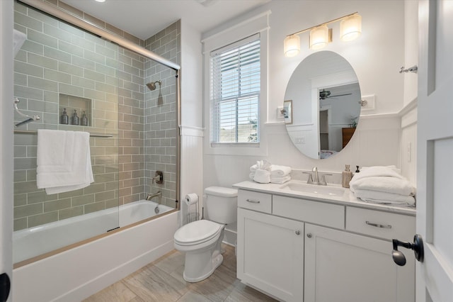 full bathroom with combined bath / shower with glass door, vanity, toilet, and ceiling fan