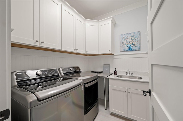 washroom featuring cabinets, washing machine and dryer, sink, and light hardwood / wood-style flooring