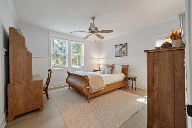 bedroom featuring ceiling fan, crown molding, and light hardwood / wood-style flooring