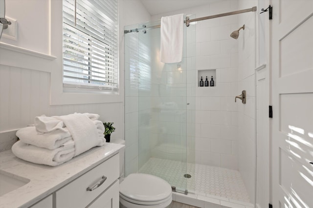 bathroom featuring a shower with door, vanity, and toilet