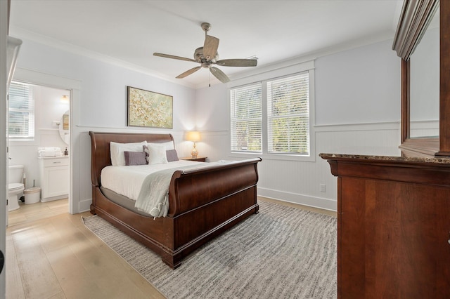 bedroom featuring connected bathroom, light hardwood / wood-style floors, ceiling fan, and crown molding