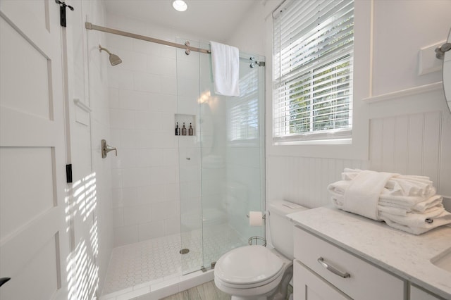 bathroom featuring vanity, a shower with shower door, and toilet