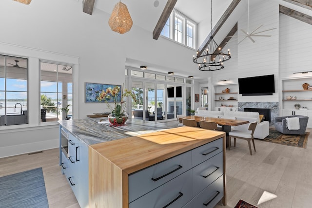 553 Old Compass Rd, Daniel Island, SC 29492 - kitchen featuring high vaulted ceiling, open floor plan, light wood-style flooring, a fireplace, and pendant lighting
